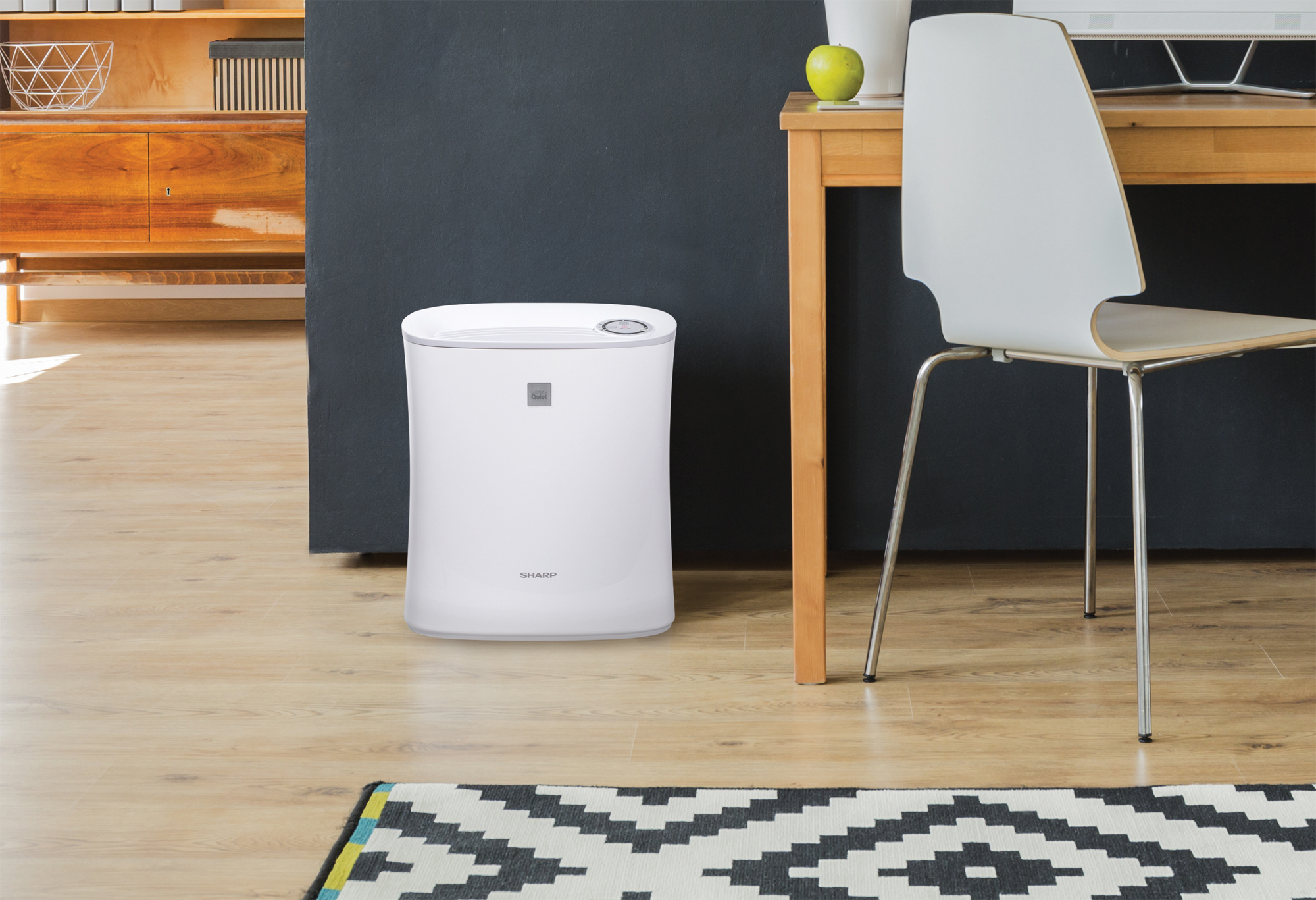 A small HEPA air purifier running near an indoor pet setup with hay baskets and separate enclosures