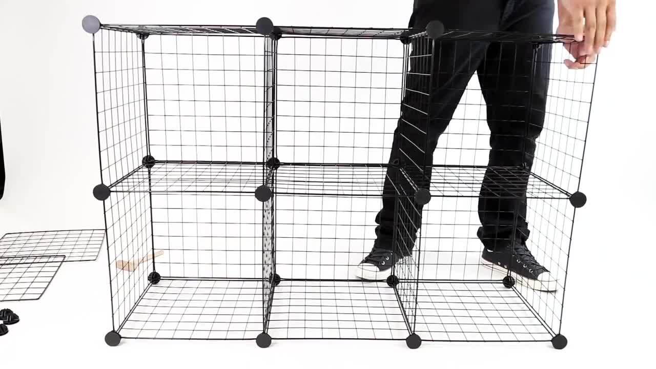 Close-up of hands fastening two wire cube grid panels together with a zip tie, building a pet enclosure frame